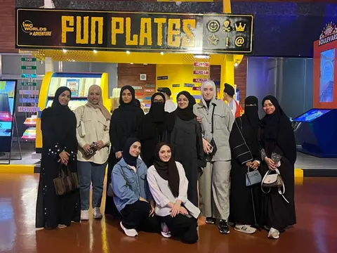 Students on the IMG Trip posing in front of the Fun Plates stand at IMG Worlds of Adventure