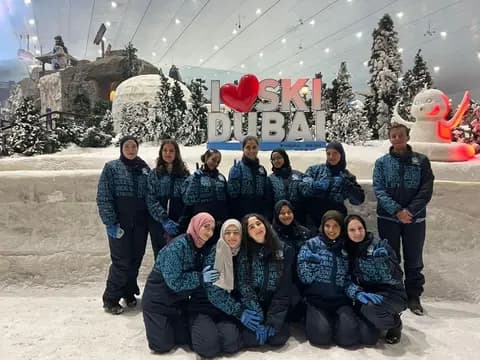 Students in ski jackets posing in front of the I love Ski Dubai sign